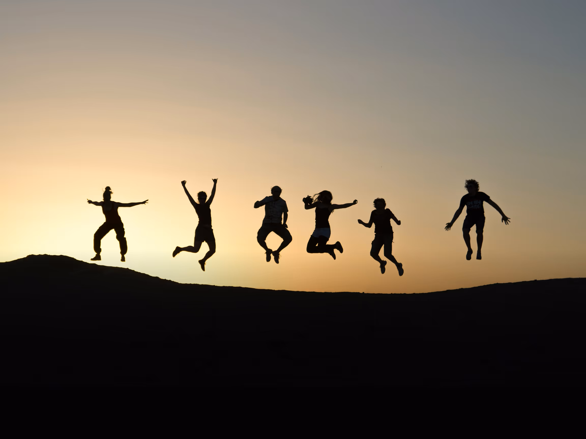 Silhouettes jumping at sunset